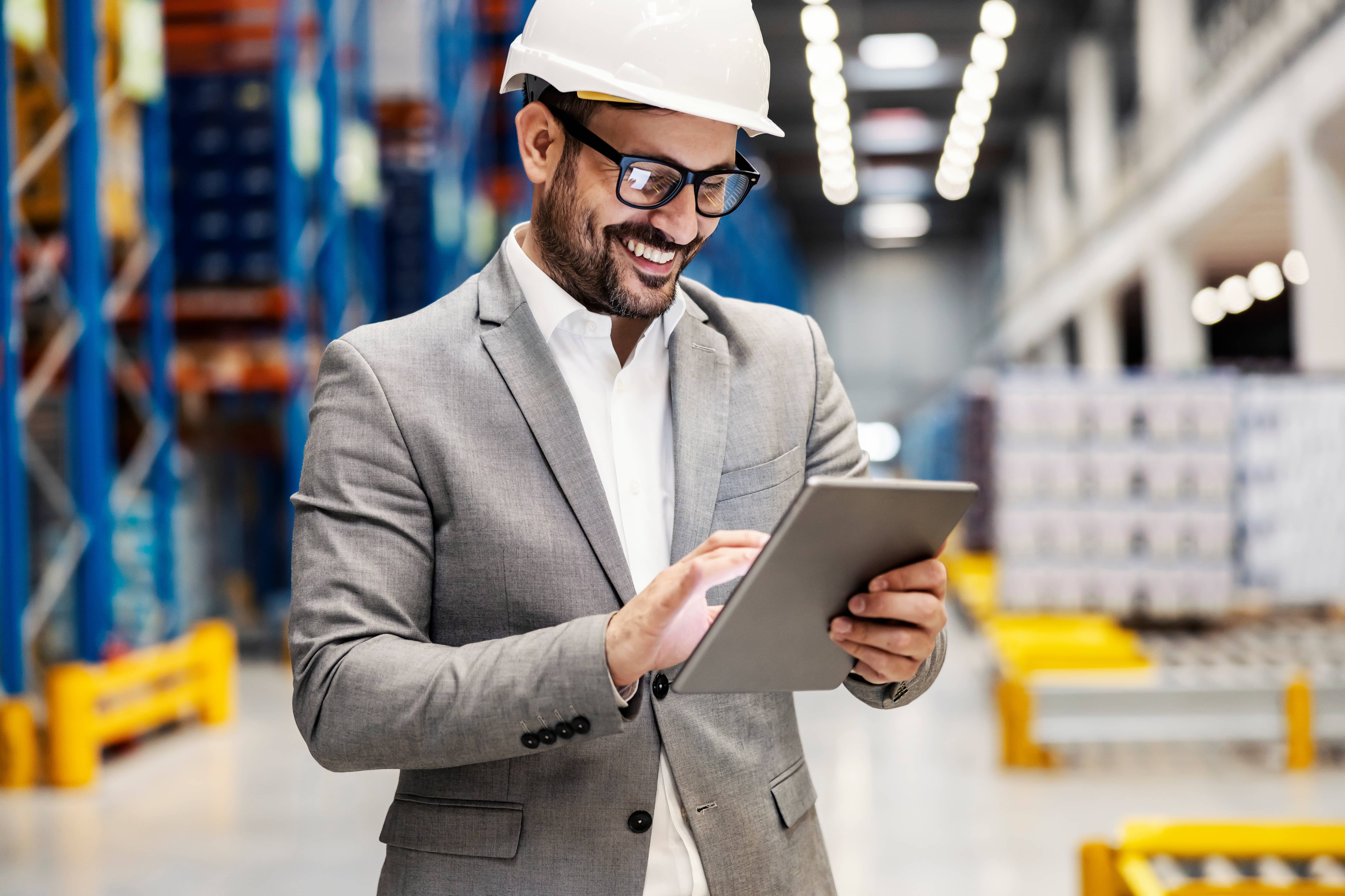 stock-photo-a-smiling-supervisor-at-distribution-center-scrolling-on-tablet-2127946742