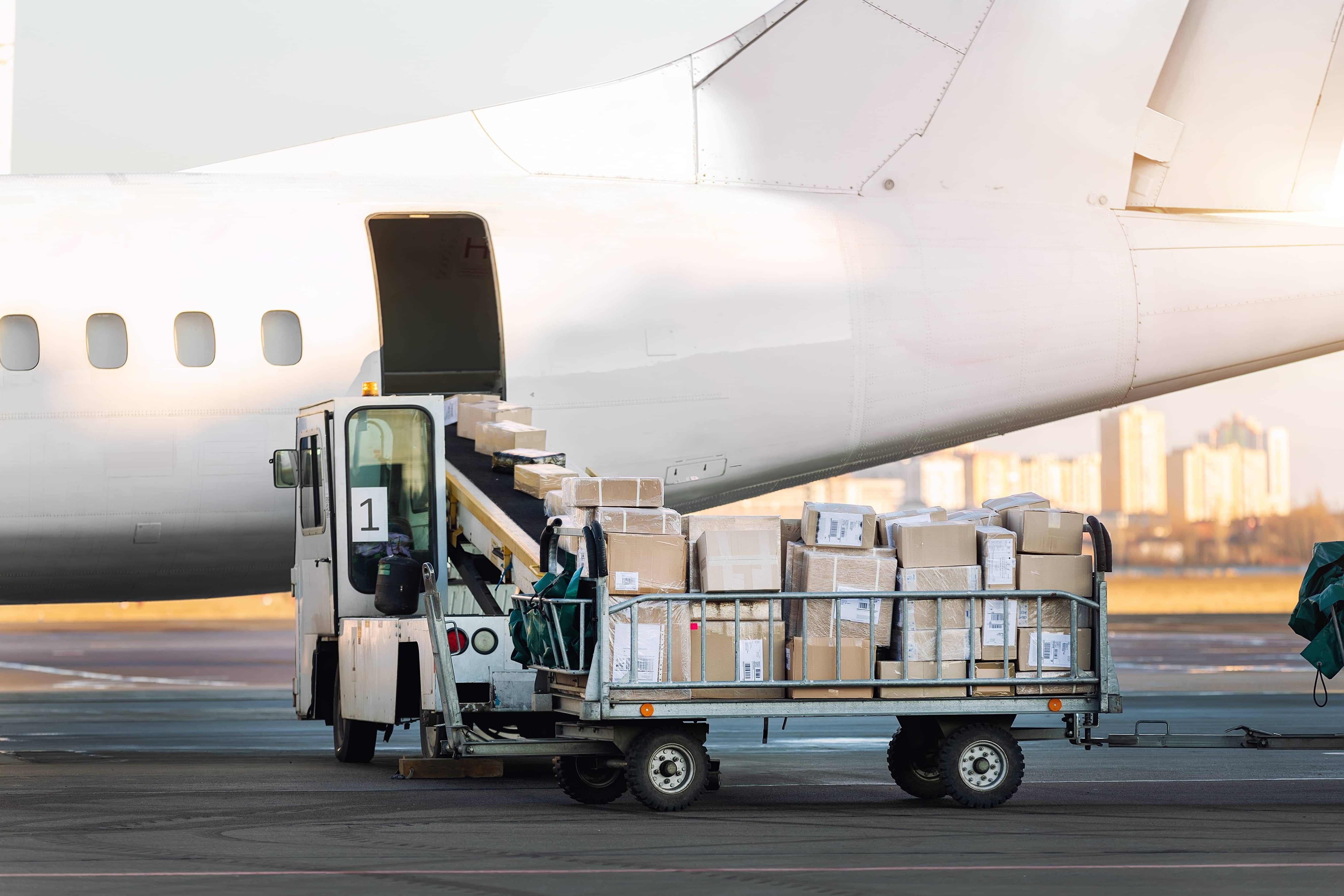 stock-photo-close-up-detail-view-of-cargo-cart-trolley-full-with-commercial-parcels-against-turboprop-cargo-2423113091