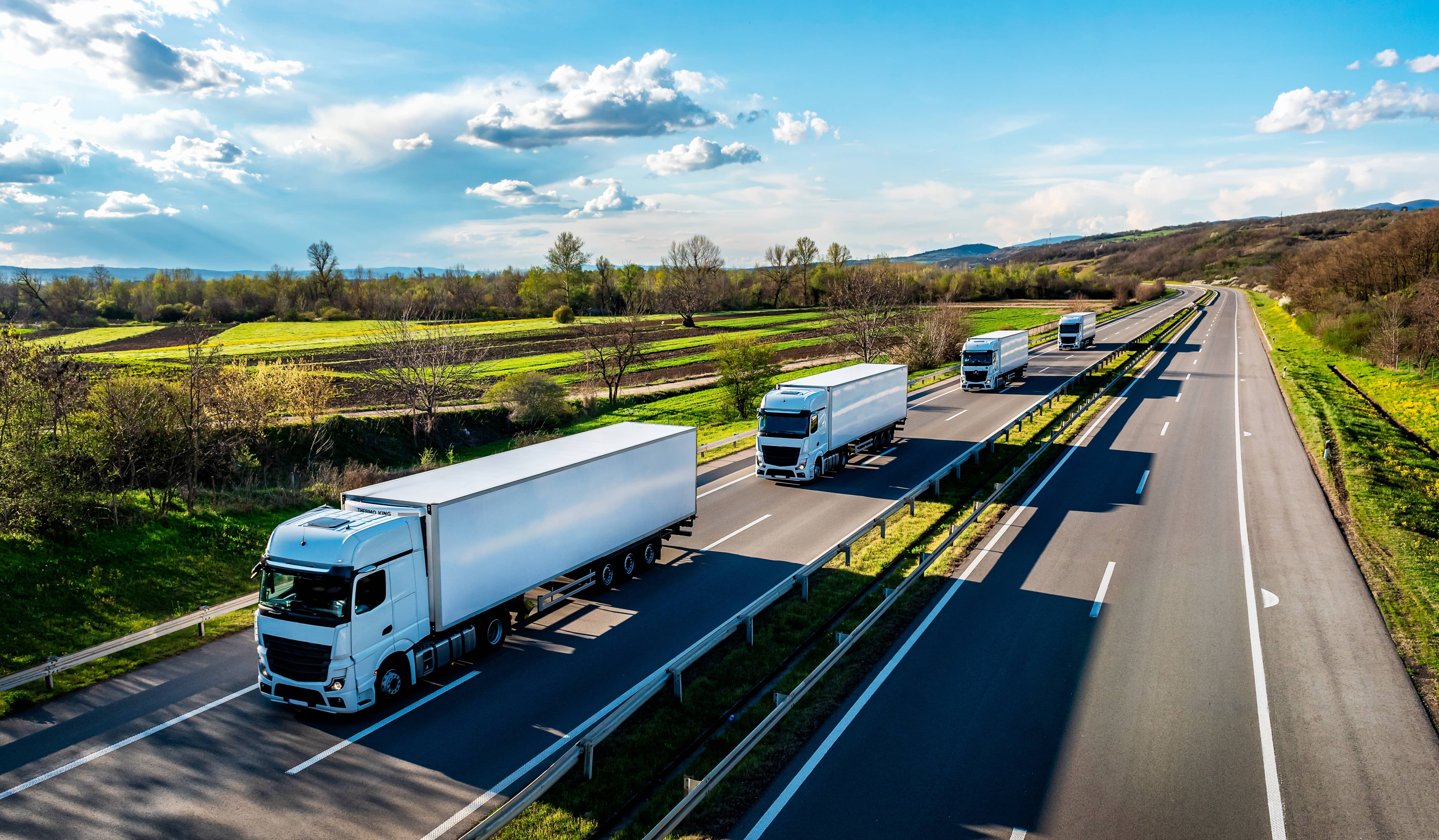 stock-photo-convoy-of-white-trucks-with-containers-on-highway-cargo-transportation-concept-in-springtime-2358050547
